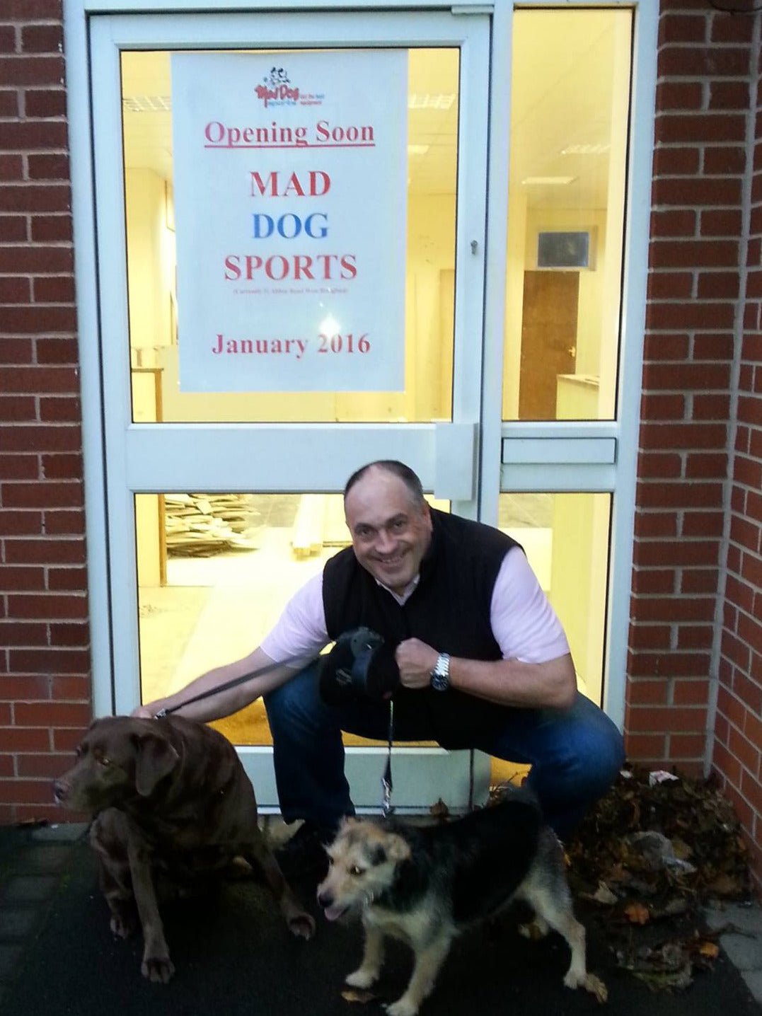 Founder Steve outside a Mad Dog Store with two dogs: Toffee (a chocolate labrador) and Suki (a small terrier)